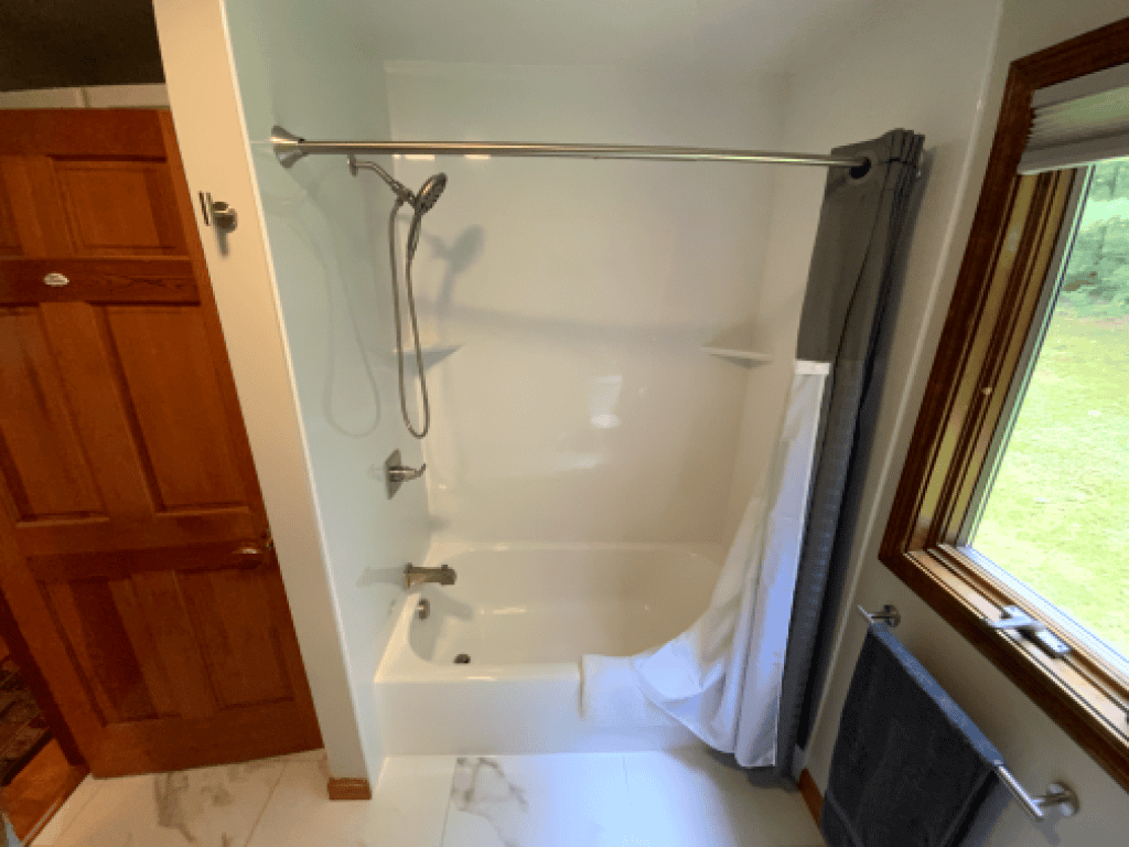 Modern bathtub with shower setup in a bright bathroom with window view.