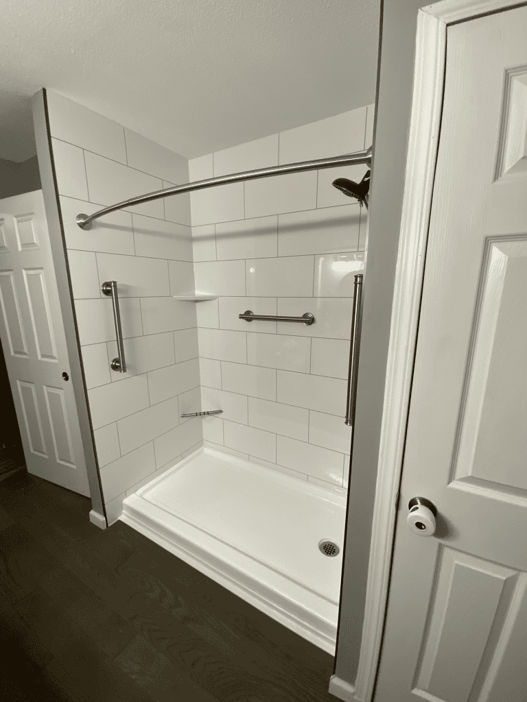 Accessible walk-in shower with grab bars and curved shower rod for safety and convenience.