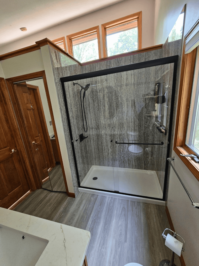 Walk-in shower with glass doors, modern fixtures, and natural lighting.