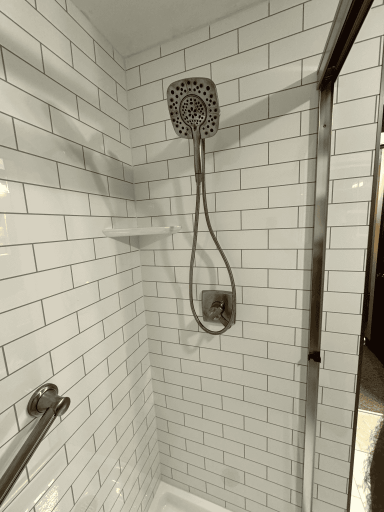 Shower head with adjustable spray in a modern bathroom with white subway tiles.