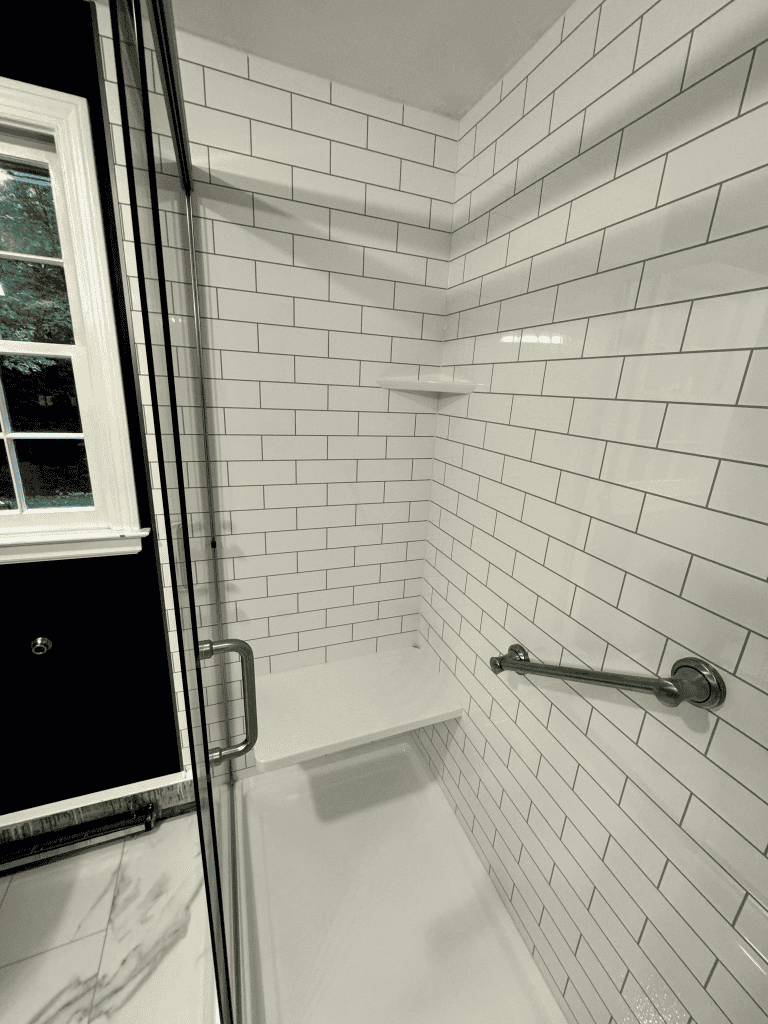 Accessible walk-in shower with white subway tiles and safety grab bar.