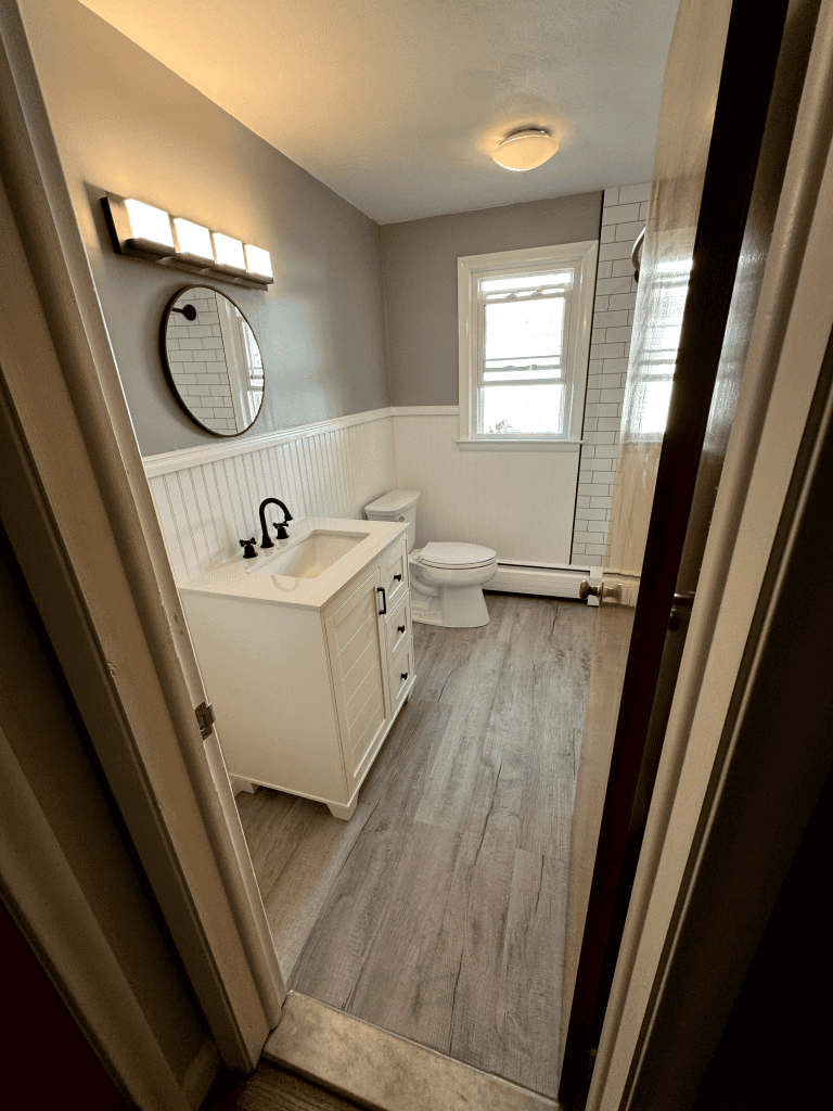 Bright and clean bathroom with a white vanity, black fixtures, and natural light from a window.