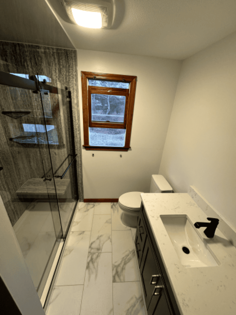 Modern bathroom with glass shower enclosure, white vanity, and marble flooring.