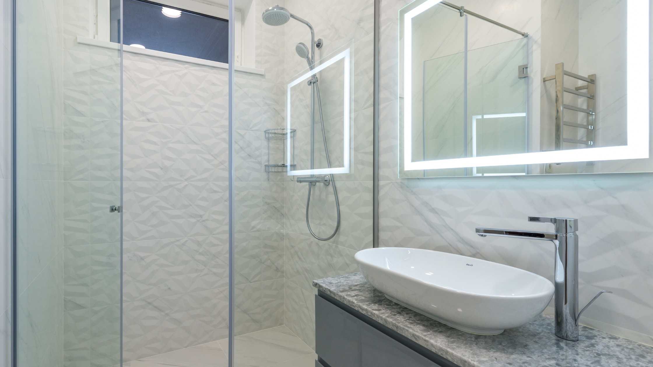 Contemporary bathroom with walk-in shower, stylish sink, and illuminated mirror for a sleek look.