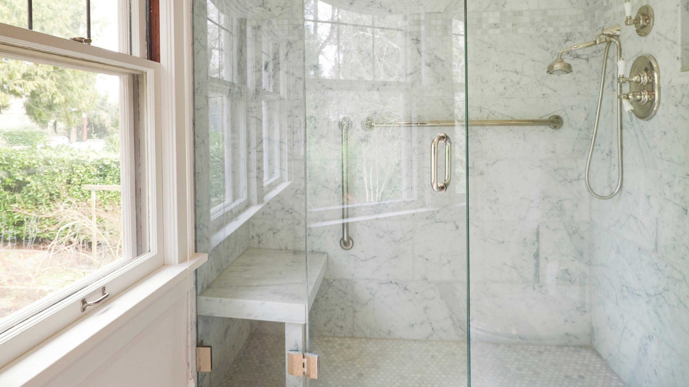 Elegant glass shower with marble walls and modern fixtures in a bright bathroom.