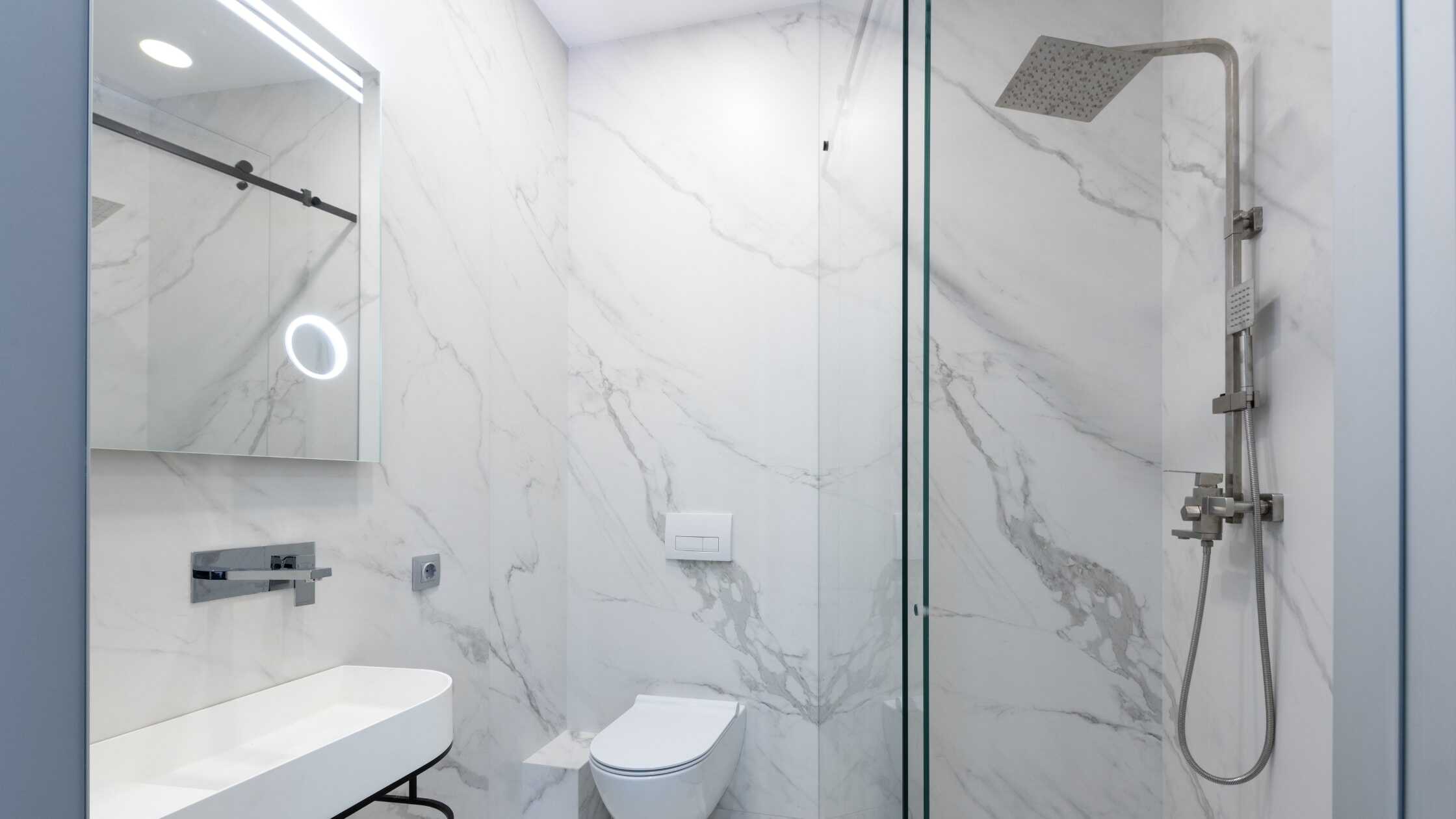 Elegant bathroom with a sleek walk-in shower featuring a rainfall showerhead and marble walls.