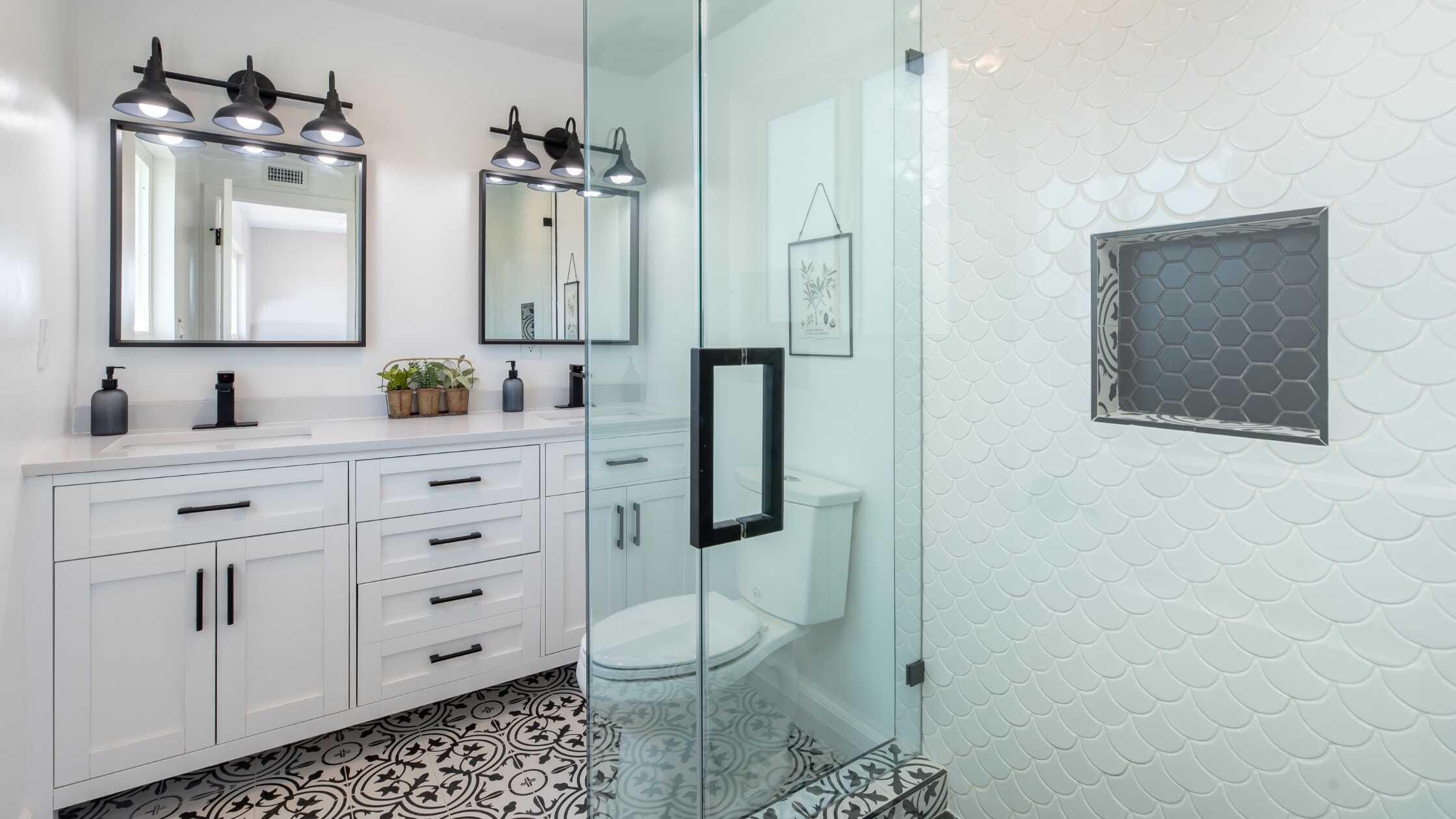 Stylish white bathroom vanity with black fixtures and large mirrors.