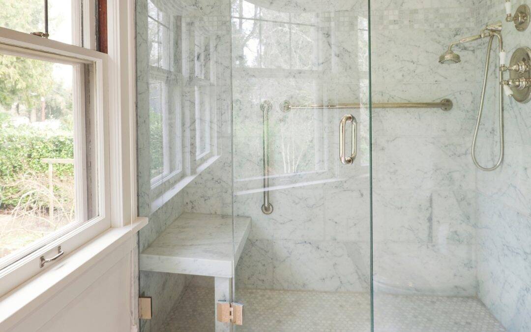 Elegant glass shower with marble walls and modern fixtures in a bright bathroom.