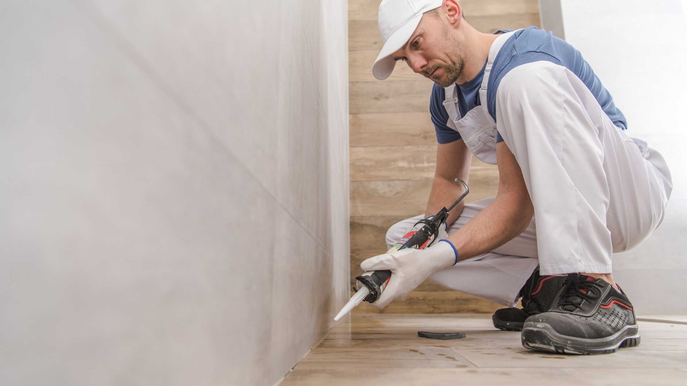 Skilled worker installing wall tiles in a modern bathroom renovation.