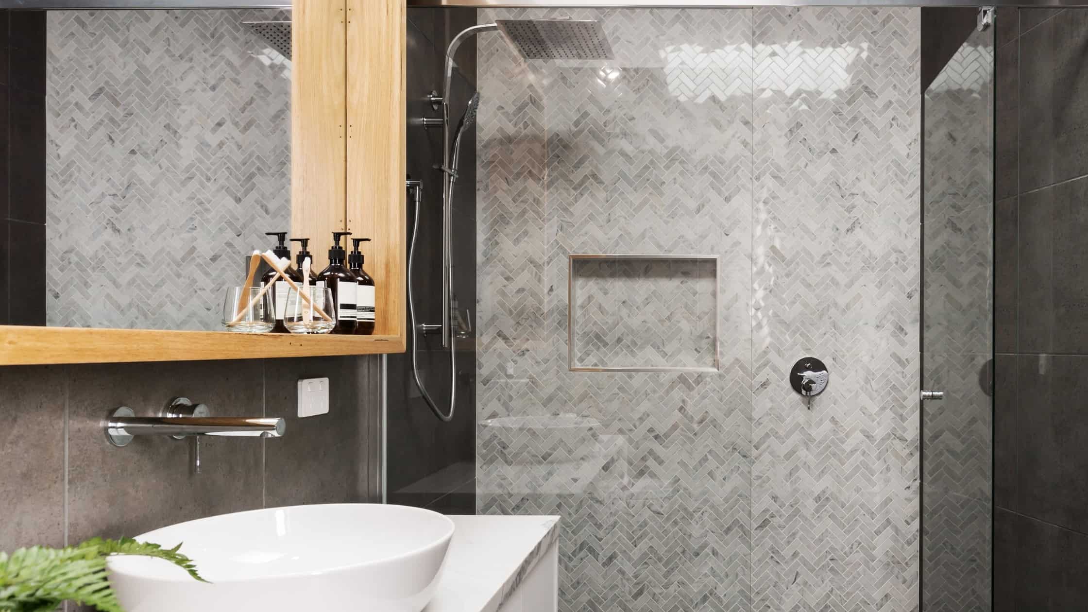 Stylish walk-in shower with textured gray tiles and built-in niche for toiletries.