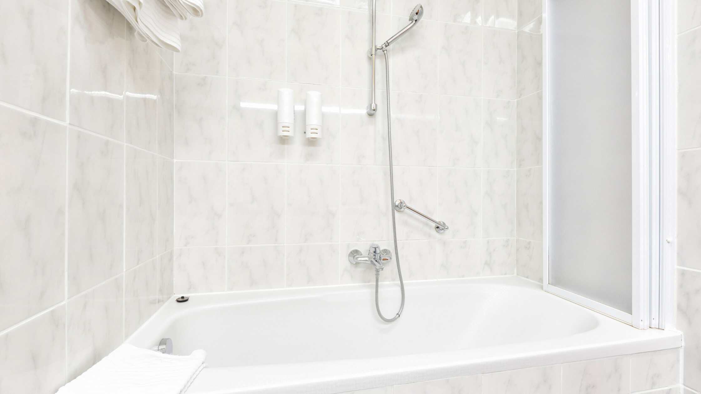 Elegant bathtub with shower fixtures in a clean, modern bathroom setting.