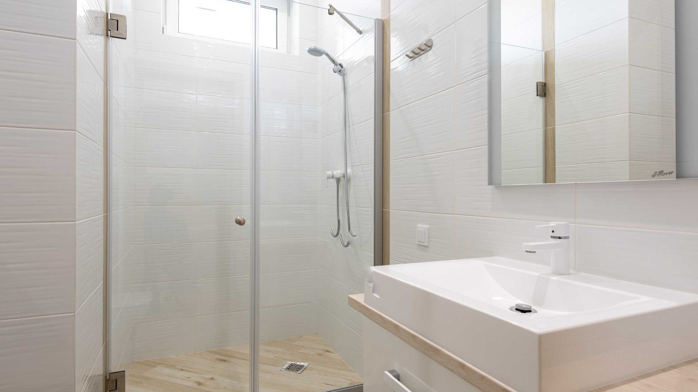 Modern bathroom with glass shower enclosure and sleek white fixtures.