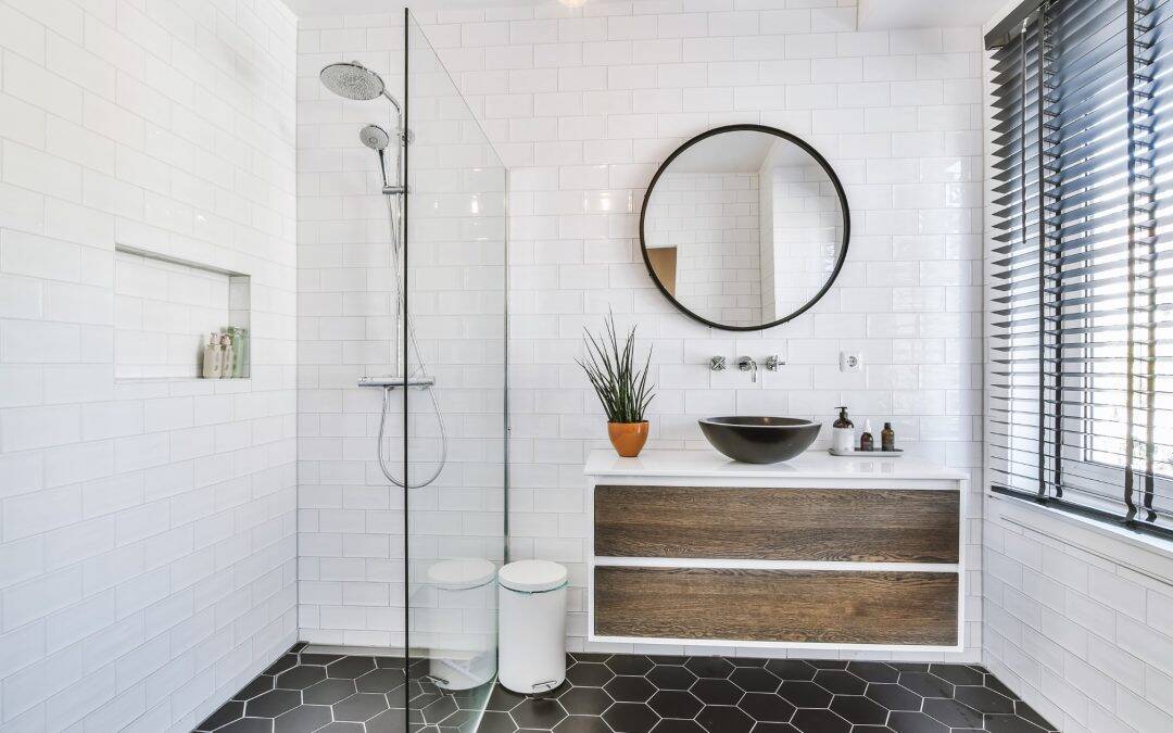 Stylish modern bathroom with walk-in shower, round mirror, and wooden vanity.