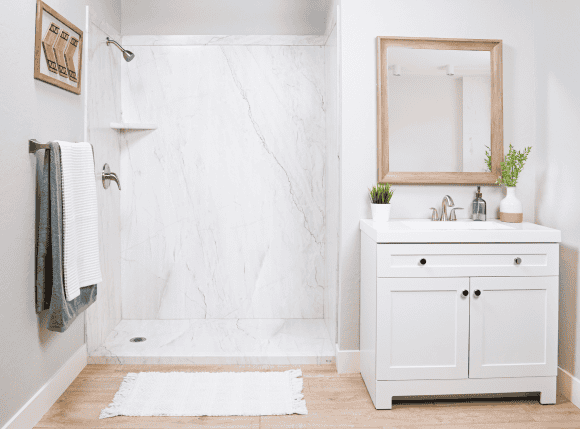 Bathroom shower with white marble tiles and a sleek white vanity.