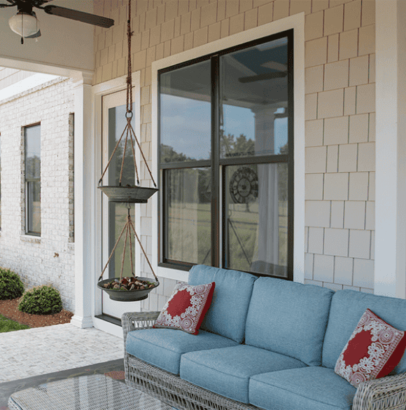 Cozy porch with hanging swing, wicker sofa, and decorative pillows for relaxing outdoor space.