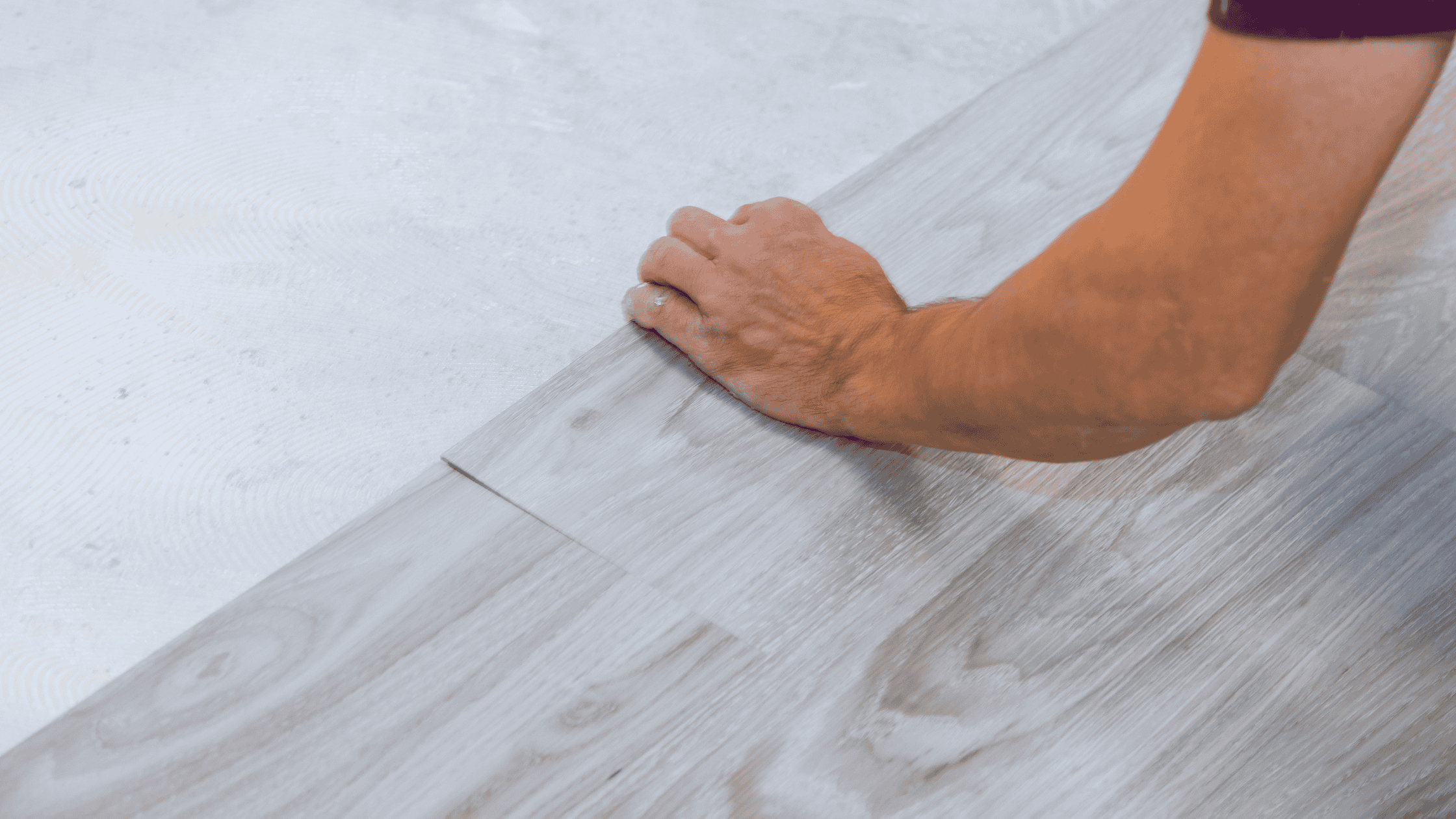 Close-up of a person installing modern vinyl flooring in a home setting.