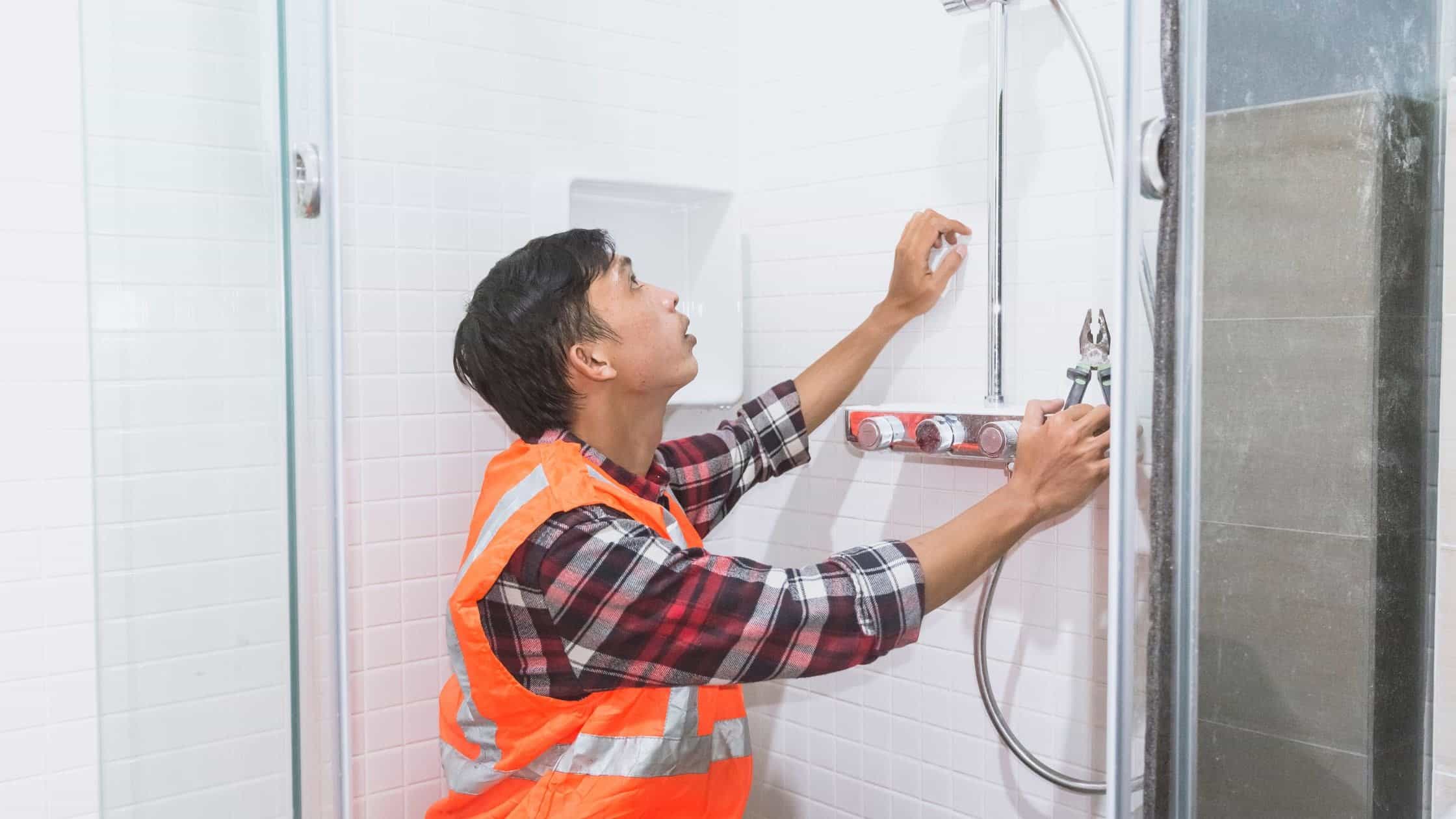 Professional shower installation in a bathroom with a worker adjusting fixtures.