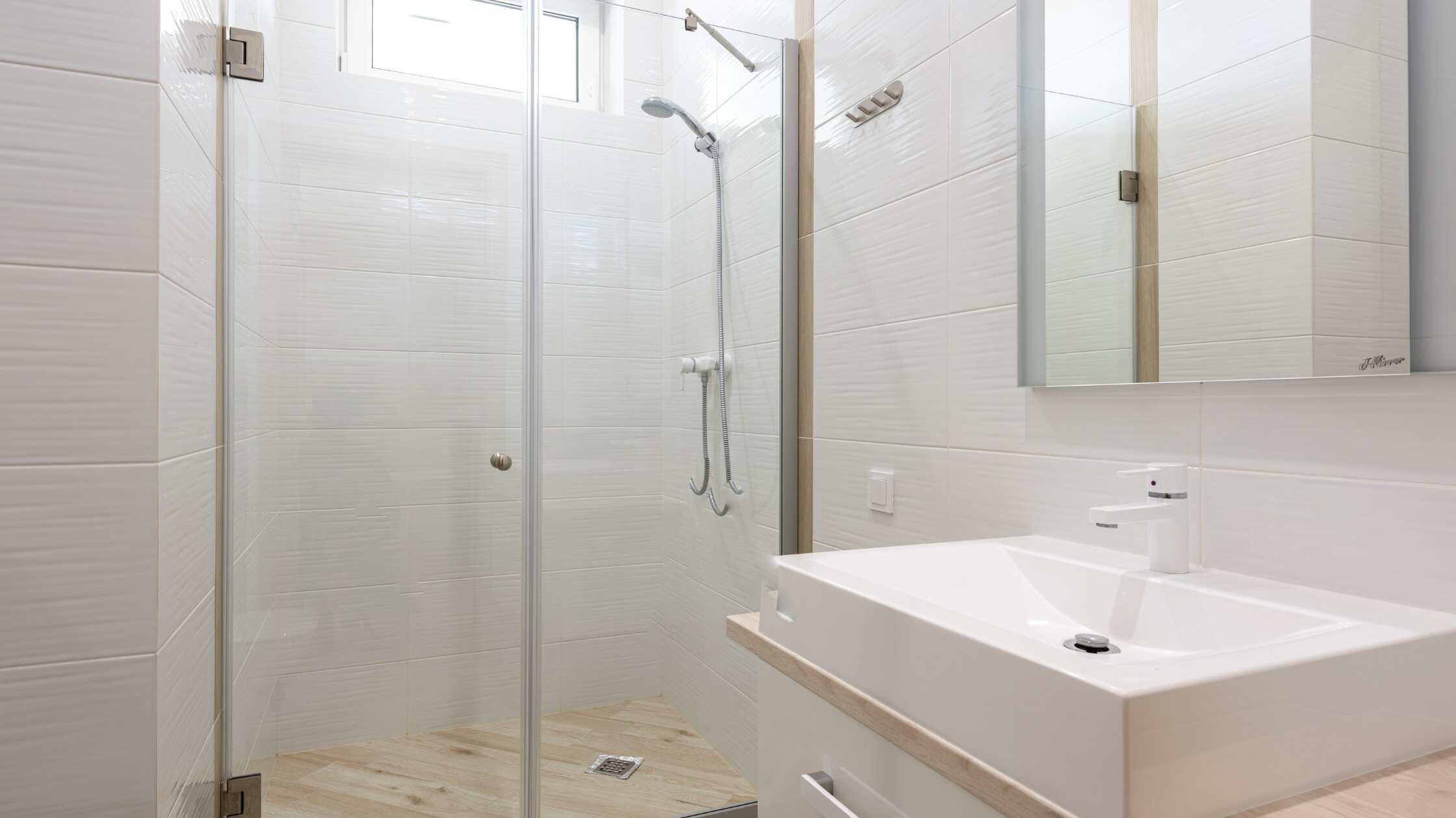 Modern bathroom with glass shower enclosure and sleek white vanity.
