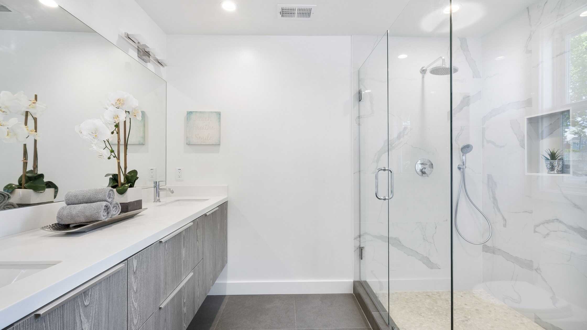 Elegant glass-enclosed shower with marble walls in a contemporary bathroom.