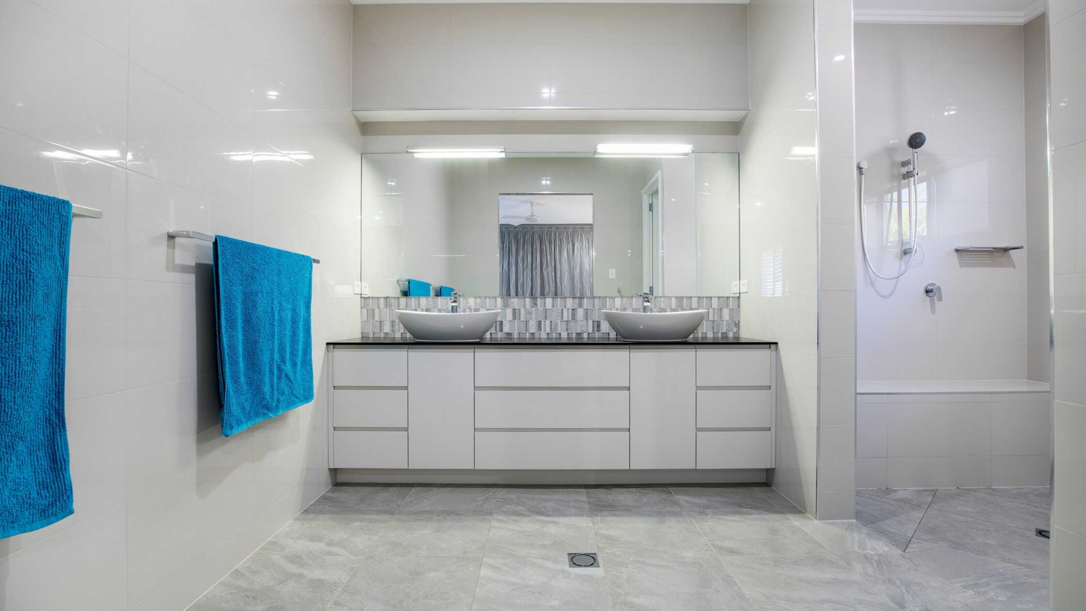 Modern bathroom with double sinks, large mirror, and sleek white cabinetry.