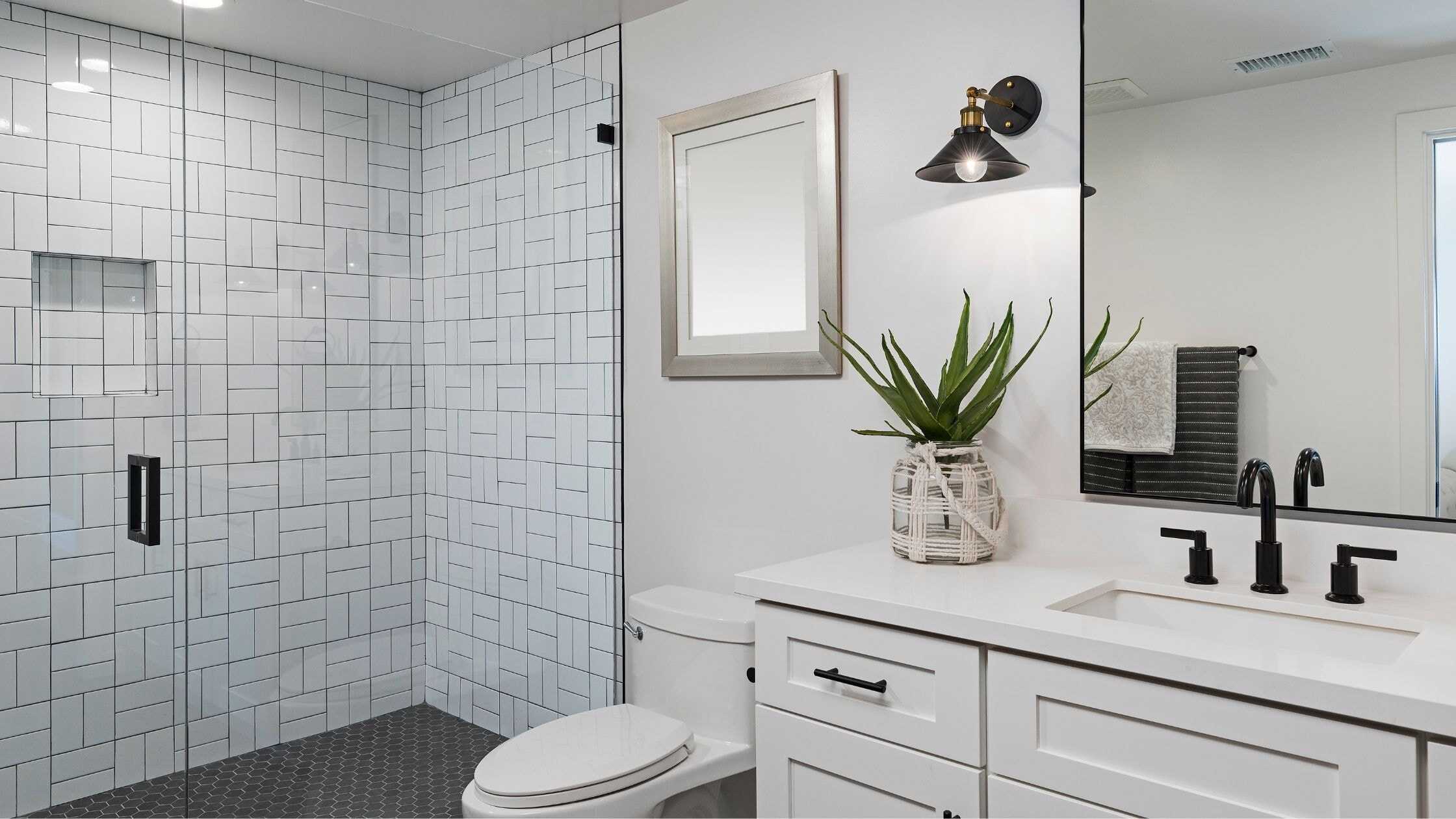 Modern bathroom with walk-in shower, white tiles, and sleek fixtures.