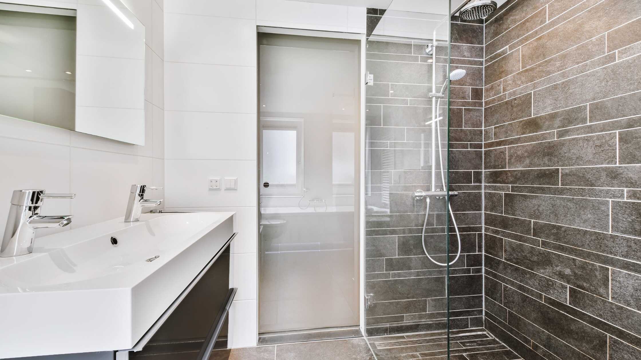 Modern bathroom with walk-in shower featuring sleek gray tile walls and glass enclosure.