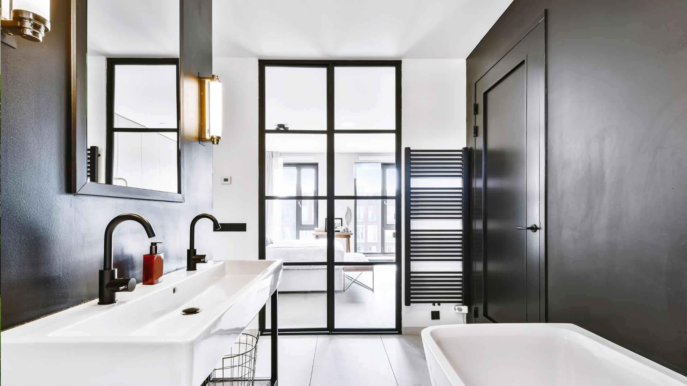 Stylish modern bathroom with dual sinks, black accents, and a glass partition.