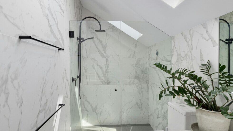 Modern marble shower with glass enclosure and black fixtures.