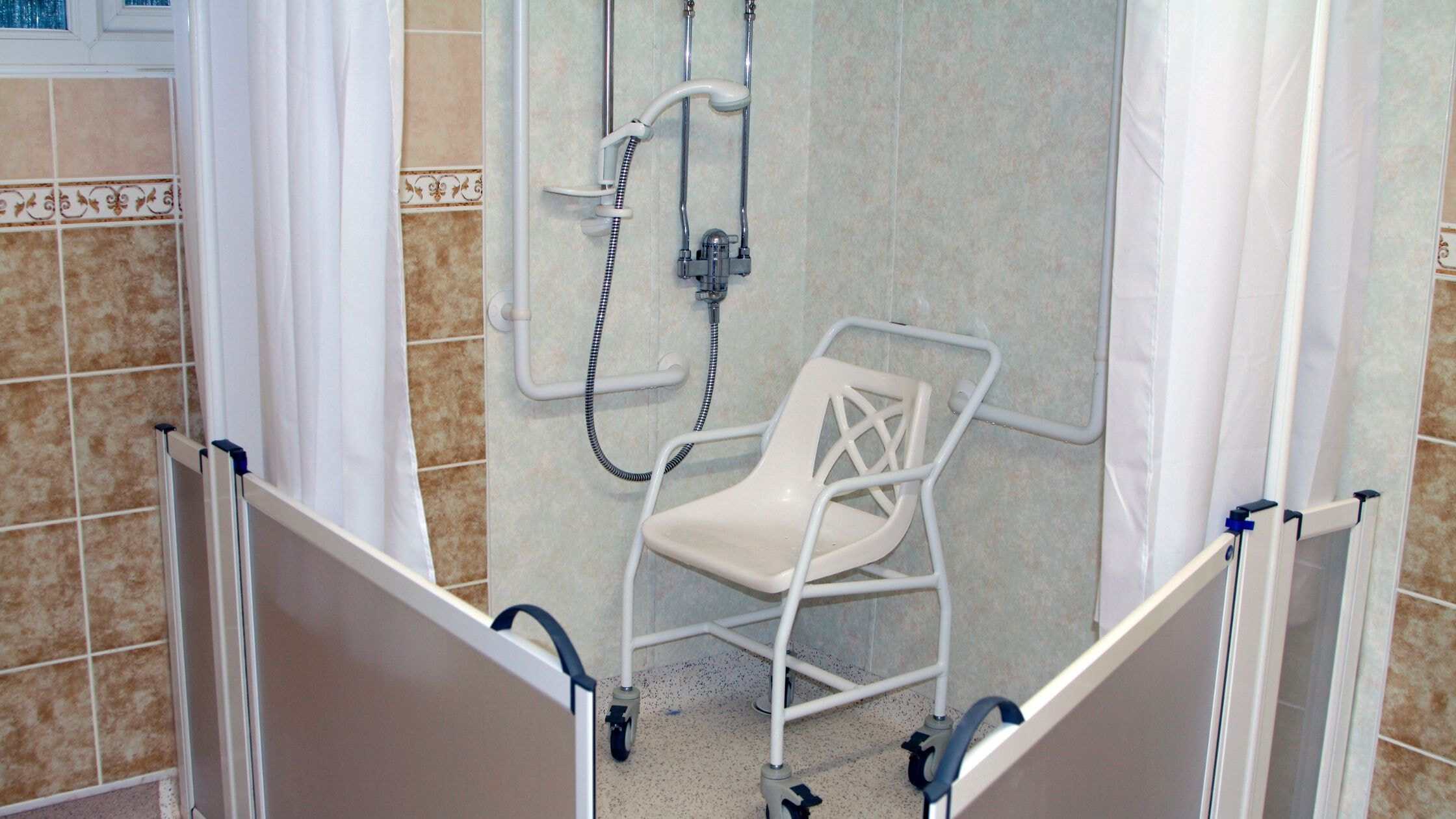 Accessible emergency shower station with chair in a bathroom setting.