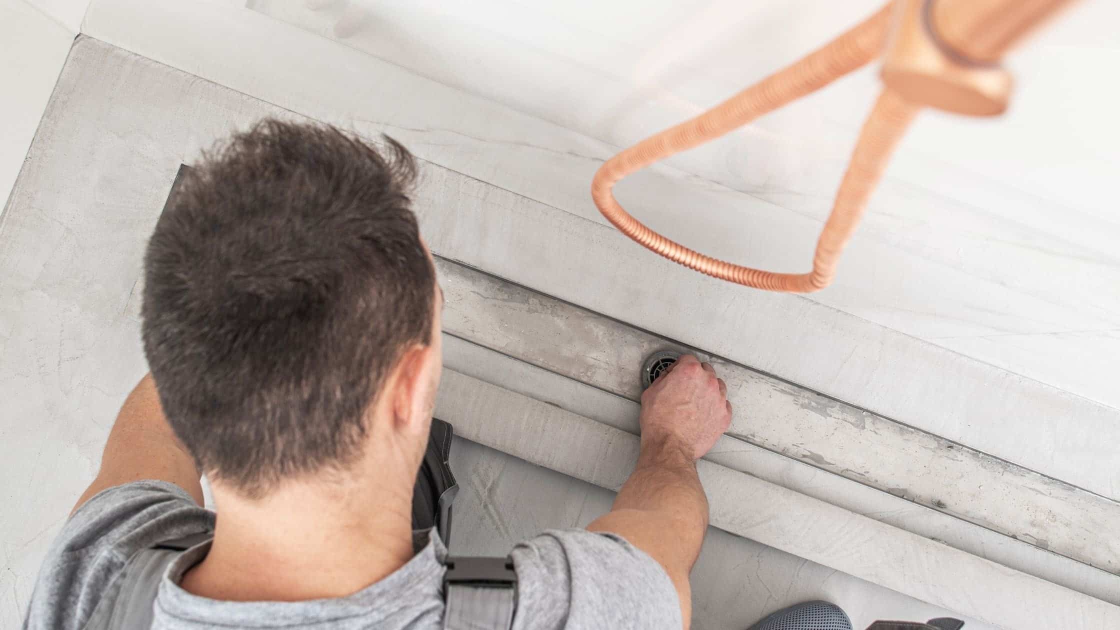 Skilled plumber fixing bathroom sink plumbing with tools in a modern bathroom.