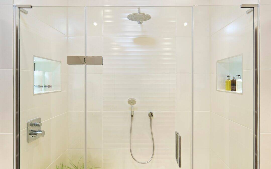 Elegant glass shower with built-in shelves and modern fixtures.