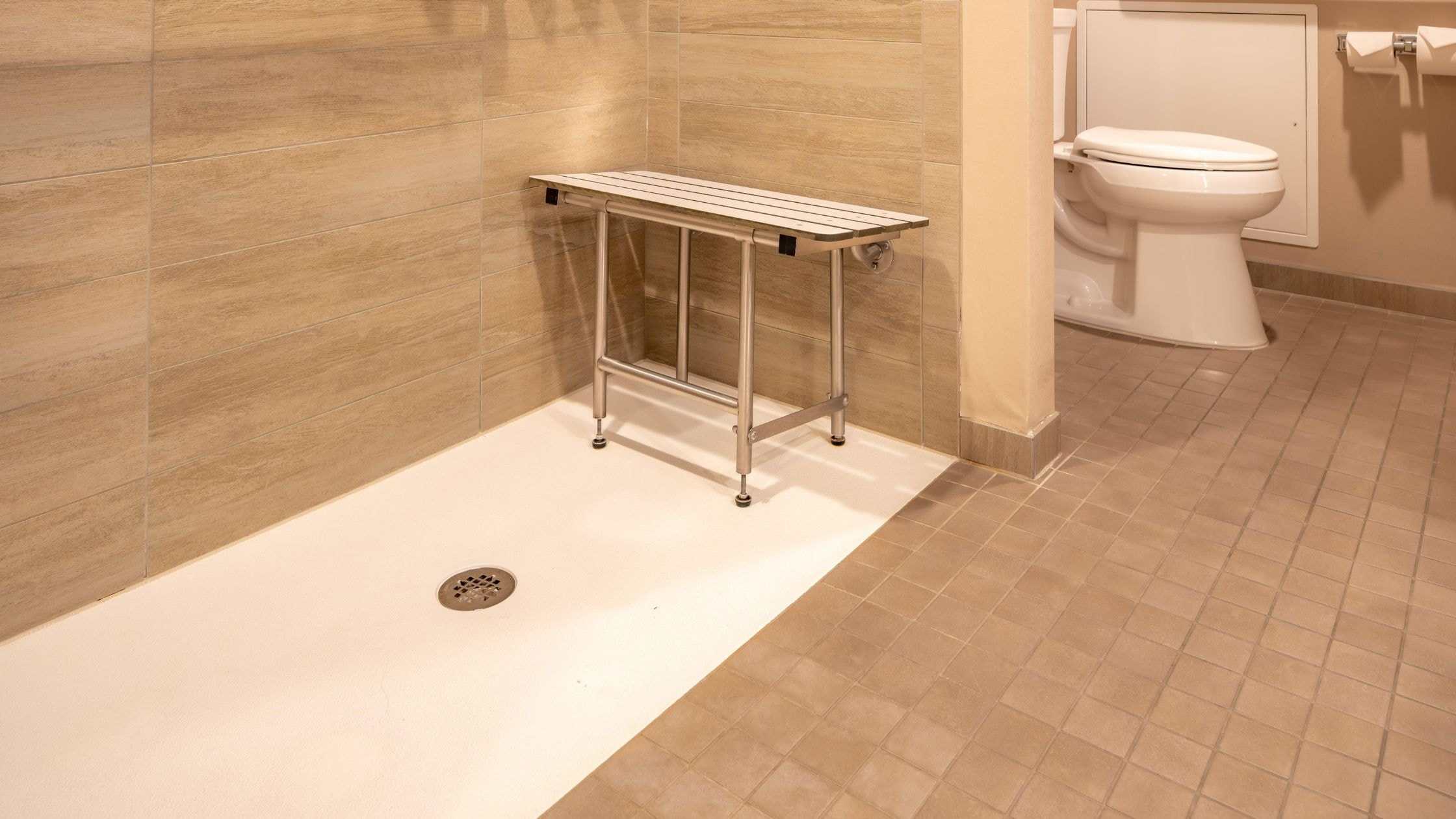 Accessible shower area with foldable bench in a modern bathroom setting.