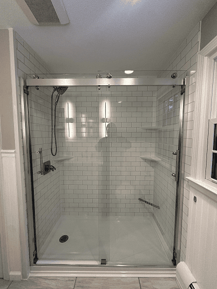 Glass shower door with chrome hardware in a contemporary bathroom.