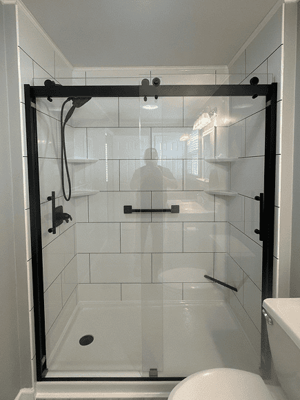 Glass shower door with black frame and built-in shelves.