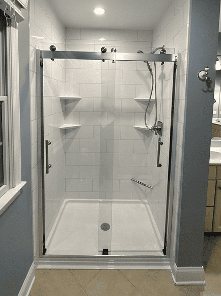 Glass shower door with chrome hardware and built-in shelves.