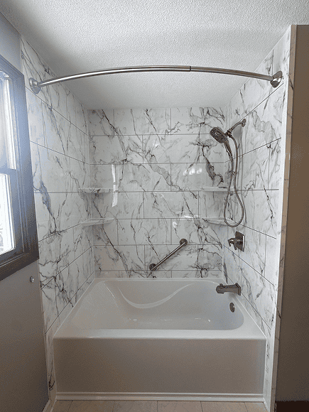 Modern Marble Shower Accessible bathtub with marble walls and handheld showerhead.