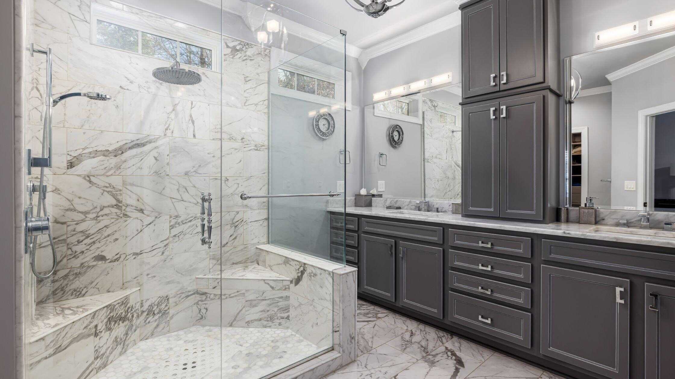 Elegant walk-in shower with marble tiles and glass enclosure in a contemporary bathroom.