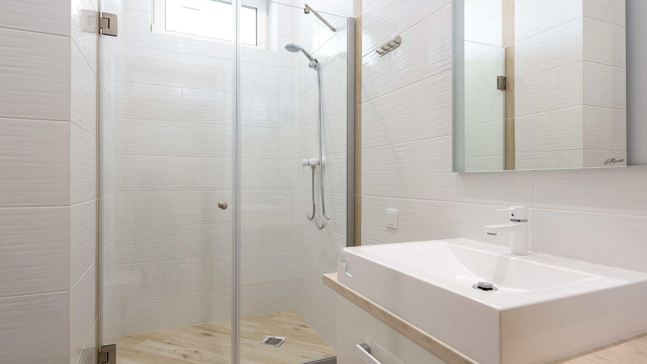 Bright modern walk-in shower with glass enclosure and sleek fixtures.
