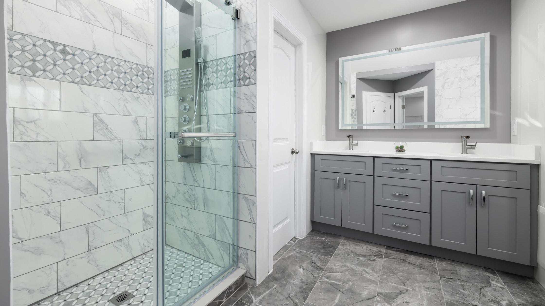 Elegant bathroom with gray vanity, large mirror, and tiled shower for a sleek, contemporary look.
