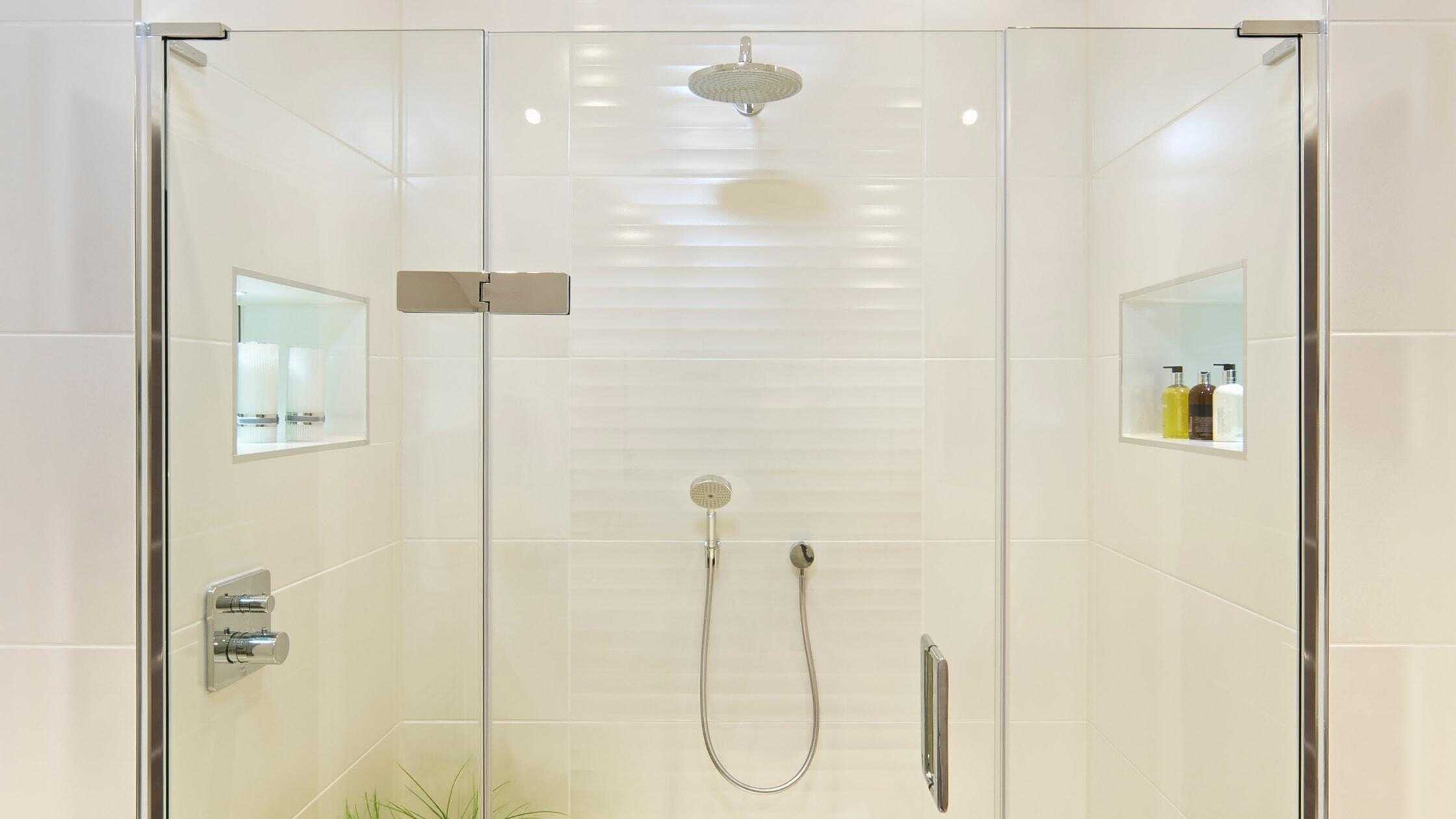 Elegant walk-in shower with glass enclosure and built-in niche storage. Perfect for contemporary bat.