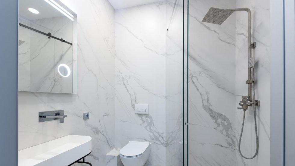 Elegant bathroom with marble walls, walk-in shower, and modern fixtures.