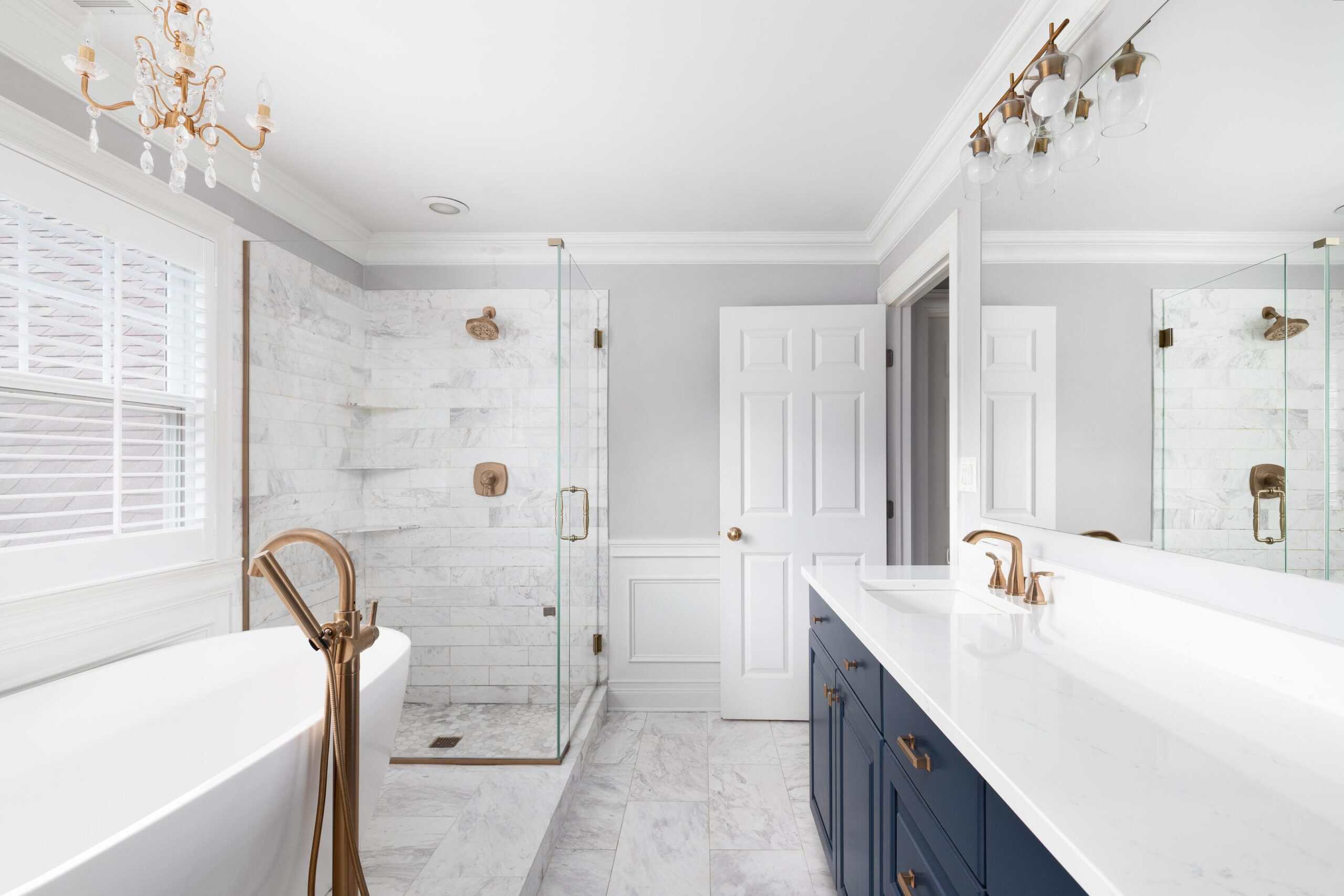 Elegant bathroom with walk-in shower, bathtub, and vanity with gold fixtures.